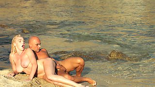 Two sexy babes have fun with a guy on the beach in a steamy scene.