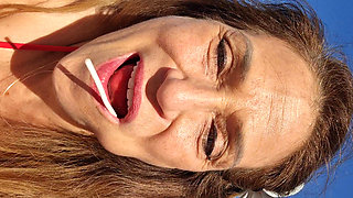 Melissa Johnson sucks and licks a cherry lollipop on the .beach